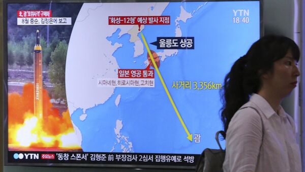 A woman passes by a TV screen showing a local news program reporting on North Korea's threats to strike Guam with missiles - 俄罗斯卫星通讯社