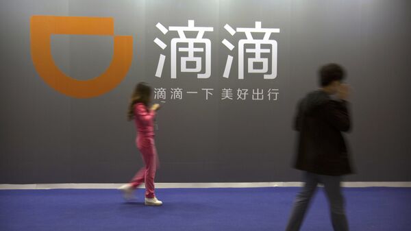 Visitors walk past a sign for Chinese ride-hailing service Didi Chuxing at the Global Mobile Internet Conference (GMIC) in Beijing - 俄羅斯衛星通訊社