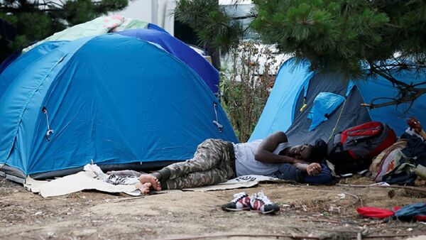 A migrant sleeps next to tents installed in a street near a shelter, opened in Porte de la Chapelle  - 俄罗斯卫星通讯社