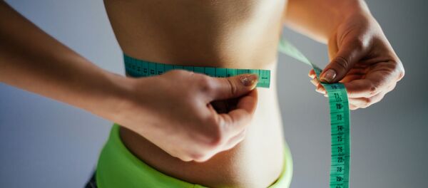 Девушка измеряет талию сантиметром - 俄罗斯卫星通讯社