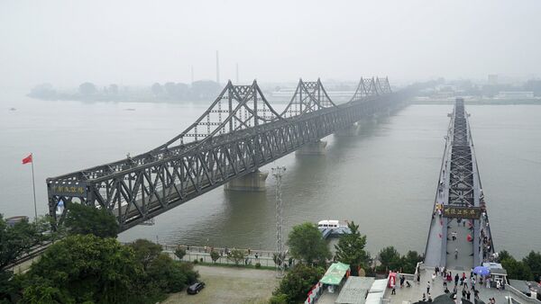 Visitors walk across the Yalu River Broken Bridge, right, next to the Friendship Bridge connecting China and North Korea in Dandong - 俄罗斯卫星通讯社