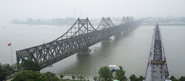 Visitors walk across the Yalu River Broken Bridge, right, next to the Friendship Bridge connecting China and North Korea in Dandong - 俄罗斯卫星通讯社