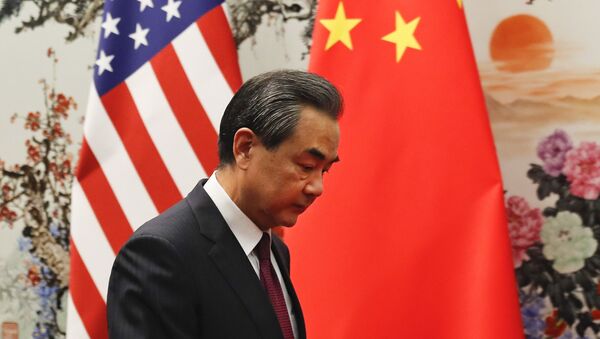 China's Foreign Minister Wang Yi walks by U.S. and Chinese national flags as he prepares to meet Secretary of State Rex Tillerson - 俄羅斯衛星通訊社