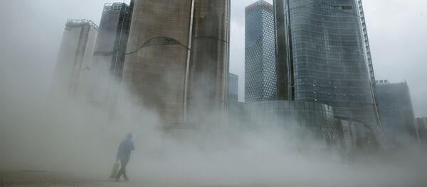 A man walks through a cloud of dust whipped up by wind at the construction site near newly erected office skyscrapers in Beijing - 俄羅斯衛星通訊社