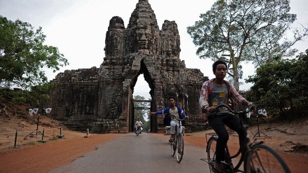 Youths cycling past an entry gate to the ancient city of Angkor Thom, part of the Angkor architectural complex in north-western Cambodia - 俄罗斯卫星通讯社
