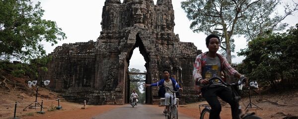 Youths cycling past an entry gate to the ancient city of Angkor Thom, part of the Angkor architectural complex in north-western Cambodia - 俄罗斯卫星通讯社