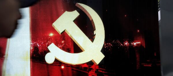 A man walks by an advertising electric panel showing the Communist Party logo - 俄罗斯卫星通讯社