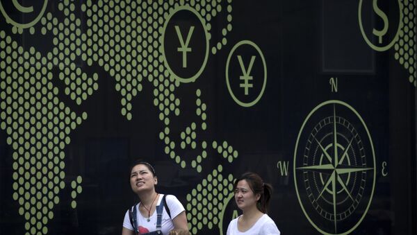 Women walk by a billboard showing a world map with foreign currency signs on display outside a bank in Beijing - 俄罗斯卫星通讯社