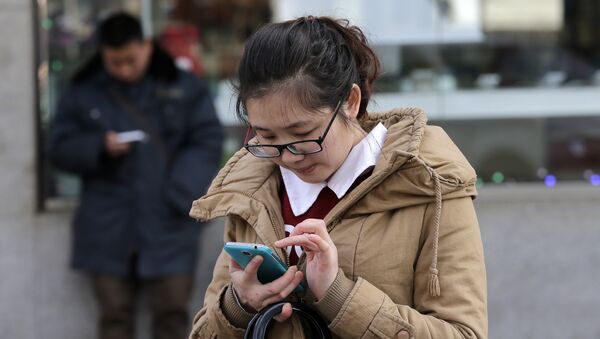 Chinese people check on their smartphones on a street in Beijing - 俄罗斯卫星通讯社