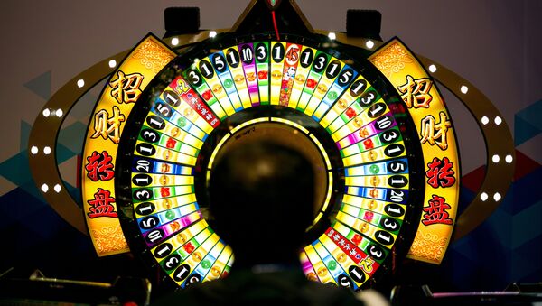 A man tries his luck at a wheel of fortune machine at the Global Gaming Expo Asia held in Macau - 俄羅斯衛星通訊社