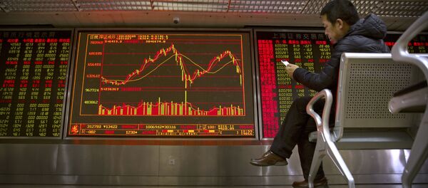 A Chinese investor uses his smartphone as he monitors stock prices at a brokerage house in Beijing - 俄羅斯衛星通訊社