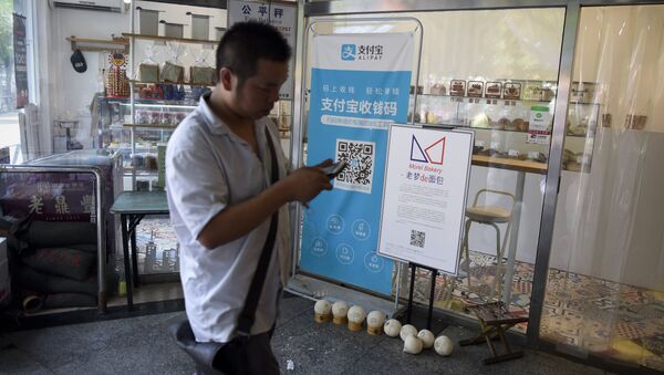 A man walking past a banner advertising the Alipay mobile payment service at a market in Beijing. - 俄罗斯卫星通讯社