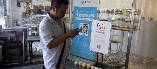 A man walking past a banner advertising the Alipay mobile payment service at a market in Beijing. - 俄罗斯卫星通讯社