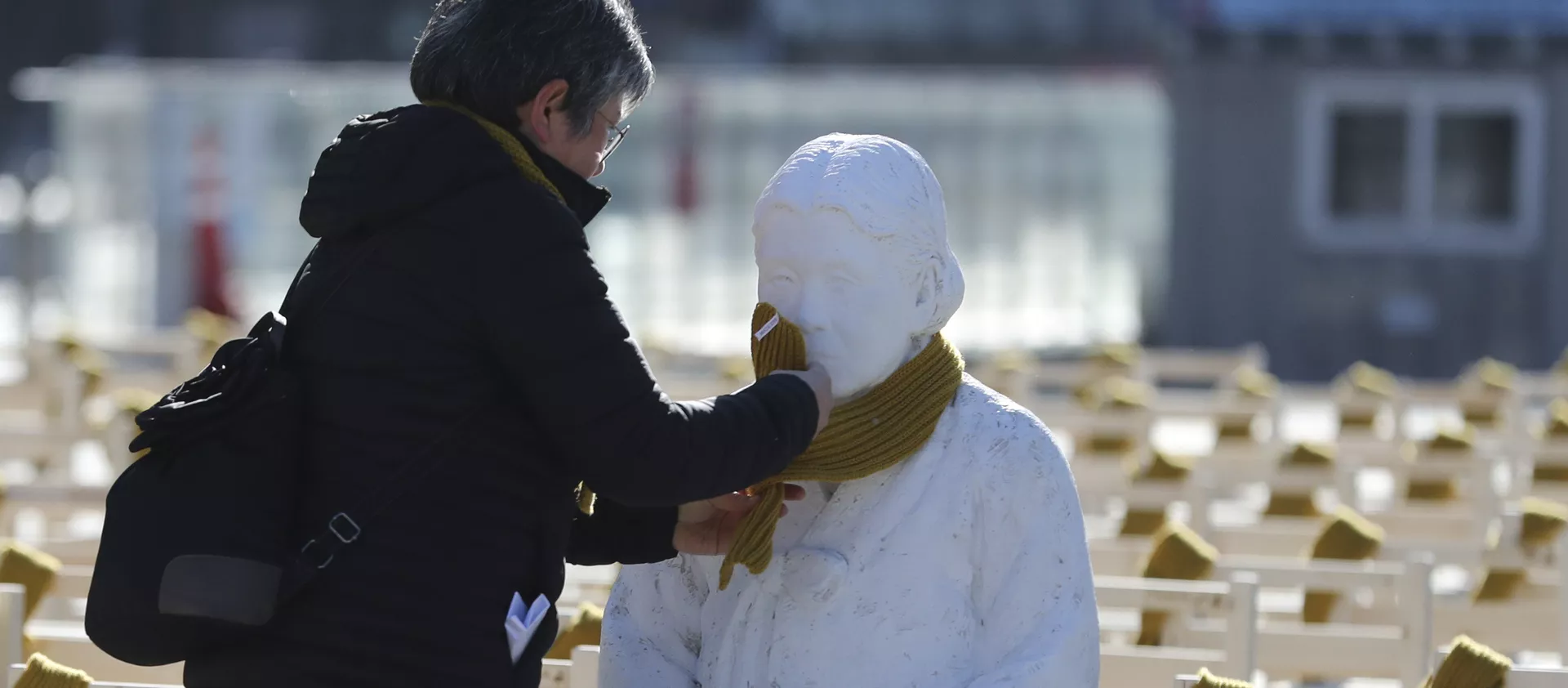 A woman puts a scarf on a statue of a comfort woman sitting in a installation of empty chairs symbolizing the victims in Seoul - 俄羅斯衛星通訊社, 1920, 29.06.2021