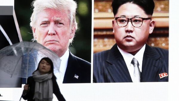 A woman walks by a huge screen showing U.S. President Donald Trump, left, and North Korea's leader Kim Jong Un - 俄罗斯卫星通讯社