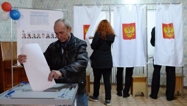 Мужчина опускает бюллетень во время голосования на избирательном участке в Крыму - 俄罗斯卫星通讯社