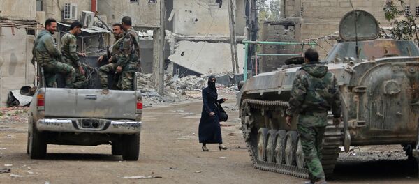 Syrian government forces' infantry fighting vehicles (IFVs) and trucks drive past damaged buildings down a street in the Eastern Ghouta town of Hazzeh - 俄罗斯卫星通讯社