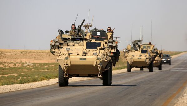 US troops sit atop an armoured vehicle on a road near the northern Syrian village of Ain Issa - 俄羅斯衛星通訊社