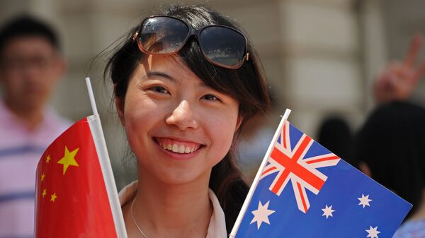 A woman holds Chinese (L) and Australian national flags - 俄羅斯衛星通訊社
