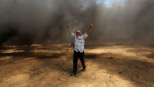 A Palestinian man walks in the smoke billowing from burning tyres during clashes with Israeli forces along the border with the Gaza strip east of Khan Yunis - 俄羅斯衛星通訊社