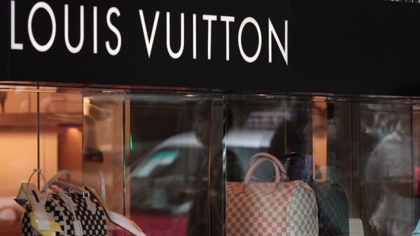 A Chinese woman leaning on a Louis Vuitton shop display window - 俄罗斯卫星通讯社