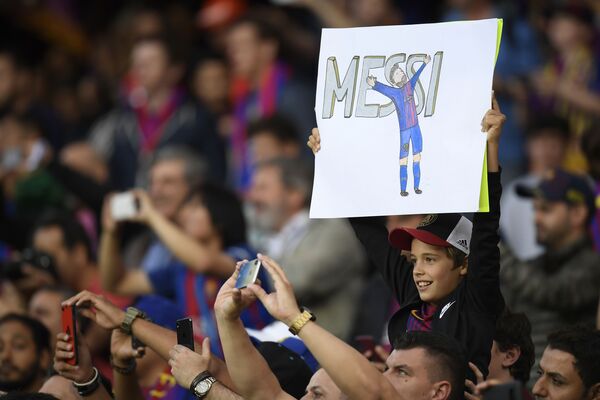 巴塞罗那。在巴塞罗那队和皇家马德里队比赛前，拿着印有巴塞罗那队前锋梅西肖像的海报的小球迷。 - 俄罗斯卫星通讯社
