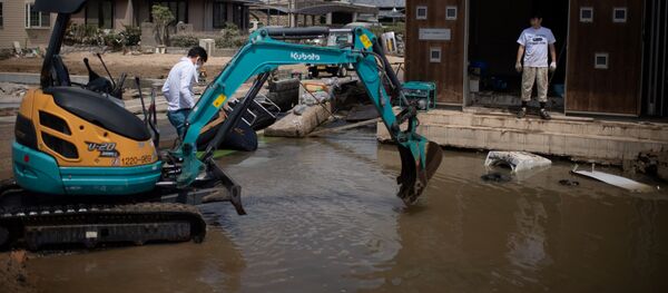 People remove water and mud with an excavator in a flood hit area in Mabi, Okayama prefecture - 俄羅斯衛星通訊社