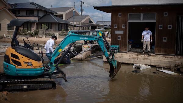 People remove water and mud with an excavator in a flood hit area in Mabi, Okayama prefecture - 俄羅斯衛星通訊社