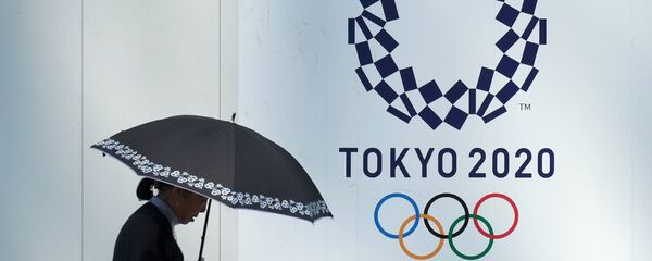 A pedestrian walks past the logo of the Tokyo 2020 Olympic and Paralympic Games adorning the wall of a construction site in Tokyo - 俄罗斯卫星通讯社