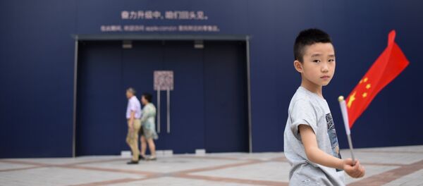 A boy holds a Chinese flag as he walks past an Apple Store undergoing renovation in Beijing - 俄罗斯卫星通讯社