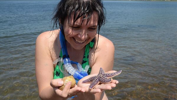 Туристка держит в руках морскую звезду на пляже острова Путятина - 俄罗斯卫星通讯社