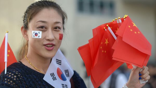 Девушка держит китайские и южнокорейские флаги около главного стадиона в Инчхон - 彩神网卫星通讯社