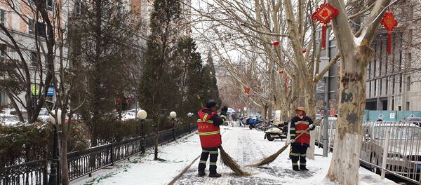 Сотрудники коммунальных служб во время уборки снега на одной из улиц Пекина. Сотрудники коммунальных служб во время уборки снега на одной из улиц Пекина. - 俄羅斯衛星通訊社