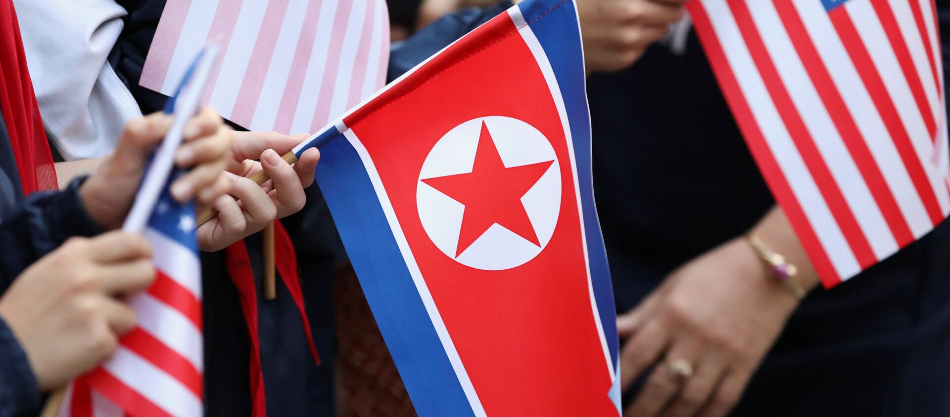 Bystanders holding North Korea and U.S. flags wait for the motorcade of U.S. President Donald Trump in Hanoi - 俄羅斯衛星通訊社, 1920, 21.06.2021