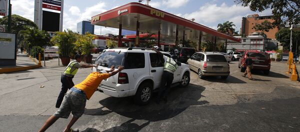 Люди подгоняют машину к заправке, у которой есть собственный электрогенератор, во время перебоев с электричеством в Каракасе, Венесуэла - 俄罗斯卫星通讯社