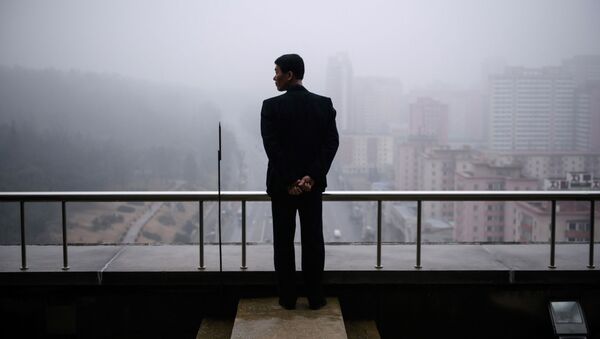 Мужчина на балконе дома в Пхеньяне в туманный день - 俄罗斯卫星通讯社