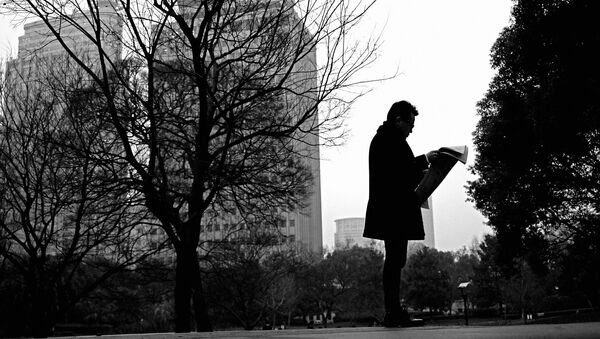 Азиатский мужчина читает газету в парке - 俄羅斯衛星通訊社