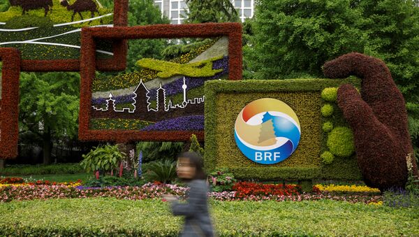 Женщина проходит мимо цветочного логотипа форума Один пояс, один путь в Пекине - 俄羅斯衛星通訊社