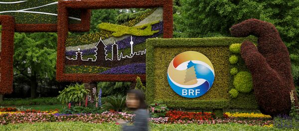 Женщина проходит мимо цветочного логотипа форума Один пояс, один путь в Пекине - 俄罗斯卫星通讯社