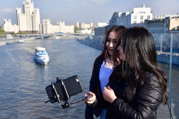在莫斯科扎里亚季耶回旋镖形浮桥上拍照的女孩。远处是科杰里尼切斯卡娅沿河街上的高楼。 - 俄罗斯卫星通讯社