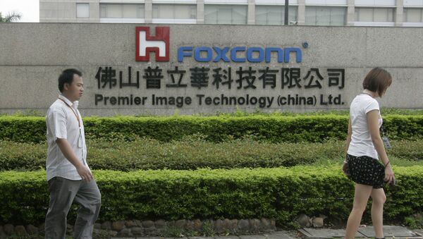 Люди проходят мимо вывески завода Foxconn в Китае - 俄羅斯衛星通訊社
