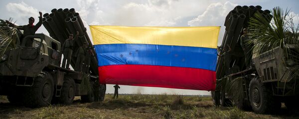 Российский истребитель Sukhoi Su-30MKV ВВС Венесуэлы летит над венесуэльским флагом, привязанным к ракетным пусковым установкам, во время военных учений Escudo Soberano 2015. Архивное фото - 俄罗斯卫星通讯社