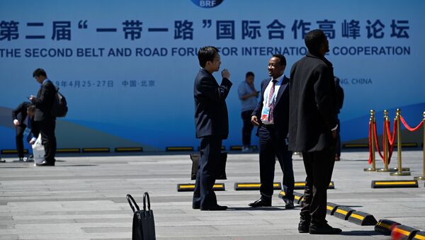 People chat in front of a billboard for the Belt and Road Forum outside the China National Convention Centre in Beijing - 俄罗斯卫星通讯社
