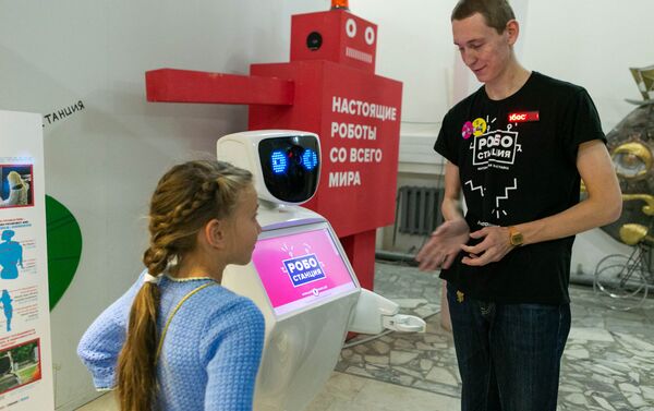 機器人站的工作人員馬克西姆為年輕的客人介紹人形機器人的各種能力 - 俄羅斯衛星通訊社