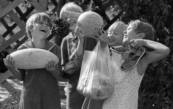 塔什乾一家孤兒院中手提懷抱香瓜、西瓜、葡萄和桃的學生們，這些都是在孤兒院院子里種植的水果。1983年。 - 俄羅斯衛星通訊社