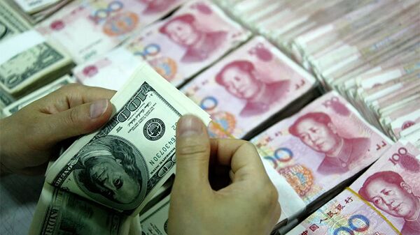 Банковский служащий пересчитывает доллары рядом с пачками юаней. - 俄羅斯衛星通訊社