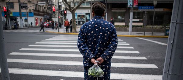 A man wearing pyjamas carries vegetables in a plastic bag in Shanghai on March 5, 2017.  - 俄羅斯衛星通訊社