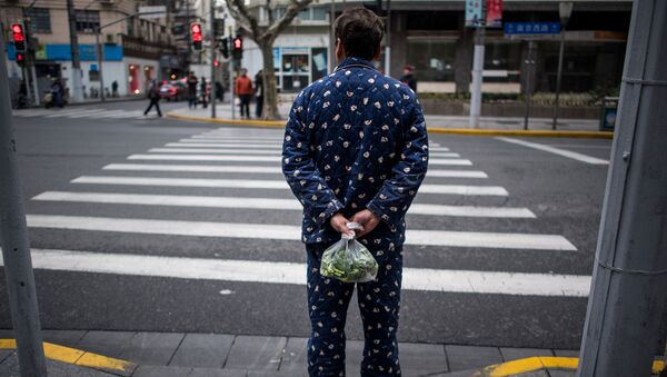 A man wearing pyjamas carries vegetables in a plastic bag in Shanghai on March 5, 2017.  - 俄罗斯卫星通讯社