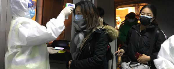 Медицинские работники в защитных костюмах проверяют температуру тела пассажиров, прибывающих из города Ухань в аэропорту Пекина, Китай - 俄罗斯卫星通讯社