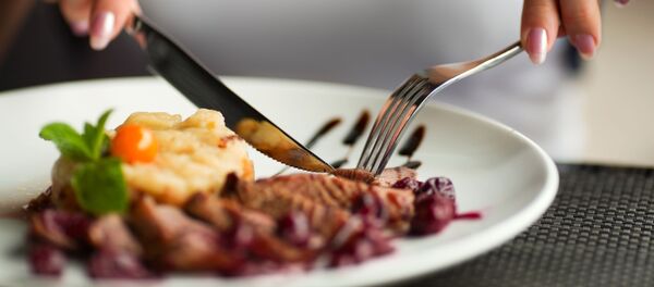 Девушка режет мясо на тарелке - 俄罗斯卫星通讯社